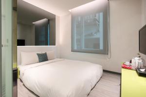 a bedroom with a white bed and white walls at CityInn Hotel Plus - Taichung Station Branch in Taichung