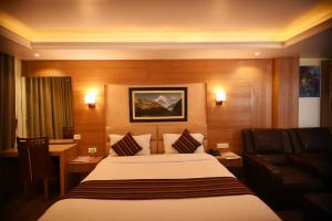 a hotel room with a large bed and a chair at Hotel Middle Path & Spa in Pokhara
