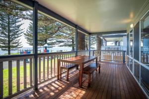 a balcony with a wooden table and bench on it at Surf Beach Holiday Park in Kiama
