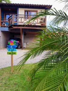 a sign in front of a house with a palm tree at casa kitinet loft bidu house in Imbituba