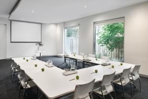 a conference room with white tables and chairs and a whiteboard at Punthill Williamstown in Williamstown