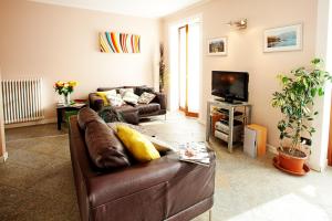 a living room with a brown leather couch and a television at Casa Giallo in Lenno