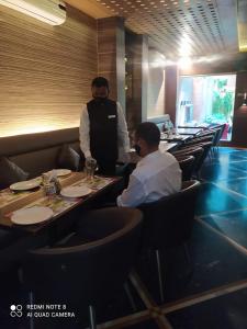 Ein paar Männer sitzen an Tischen in einem Restaurant. in der Unterkunft Hotel Plaza in Mumbai