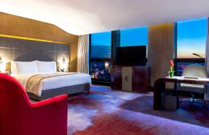 昆明市にあるソフィテル クンミンのベッド、デスク、テレビが備わるホテルルームです。