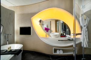 uma casa de banho com um espelho redondo e um lavatório em Sofitel Kunming em Kunming