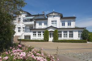 une grande maison blanche avec des fleurs devant elle dans l'établissement Villa Hoffnung Wohnung 2, à Kellenhusen