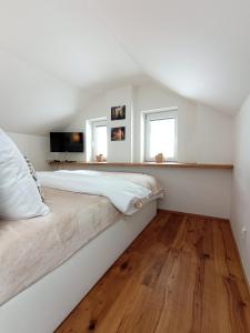 Habitación blanca con cama grande y suelo de madera. en Brunetti Apartmány Jeseníky, en Karlovice