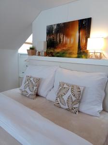 1 cama con almohadas blancas y una pintura en la pared en Brunetti Apartmány Jeseníky, en Karlovice