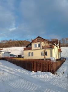 a house with a fence in the snow at Brunetti Apartmány Jeseníky in Karlovice