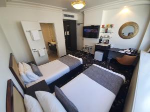 土乌巴Burke and Wills Hotel Toowoomba的有两张床和一张书桌的酒店房间