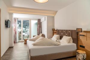 a bedroom with a large white bed and a window at Aktivhotel Pehab in Ramsau am Dachstein