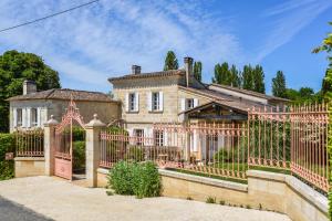 een groot huis met een hek ervoor bij La Closerie de Fronsac in Saint-Michel-de-Fronsac
