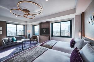 神戸市にあるザ ロイヤルパーク キャンバス 神戸三宮のベッド2台とソファがあるホテルの部屋