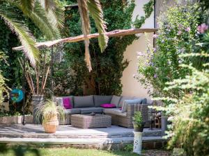 a patio with a blue couch and some plants at Chambre d'Hôtes Villa Ambrosia in Narbonne