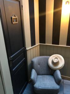 une chaise bleue avec un chapeau assis à côté d'une porte dans l'établissement Aux 13 Arches, à Portbail