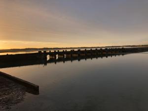 een brug over een waterlichaam bij zonsondergang bij Aux 13 Arches in Portbail