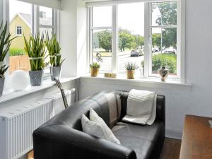 スケーエンにある4 person holiday home in Skagenの窓付きのリビングルーム(黒い革張りのソファ付)