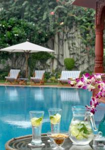 a table with drinks and flowers on it next to a pool at The Grand Imperial - Heritage Hotel in Agra