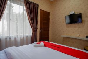 a bedroom with a bed and a tv on the wall at RedDoorz @ Jalan Majapahit Semarang in Alastuwo