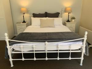 a bed with a white bed frame and two lamps at Aroha Studio in Katoomba