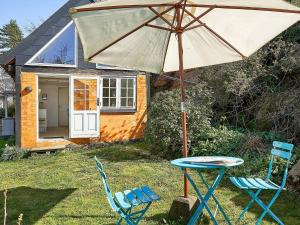 una mesa y dos sillas y una sombrilla frente a una casa en 2 person holiday home in Svaneke-By Traum, en Svaneke 14 fotos más