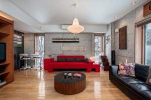 a living room with a red couch and a table at Kitanishi 3 by H2 Life in Kutchan