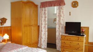 a bedroom with a bed and a television on a dresser at Ferienhaus Wurzelbergblick in Masserberg