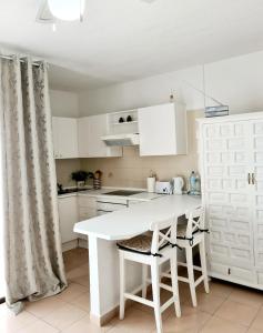 una cocina con armarios blancos y una mesa y sillas blancas. en Studia Puerto de Santiago, en Puerto de Santiago