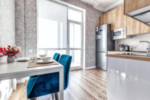 une cuisine avec une table blanche et des chaises bleues dans l'établissement Raisson Ahotel B172, à Astana