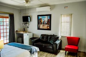 a bedroom with a bed and a couch and a chair at Rue Guesthouse in Postmasburg