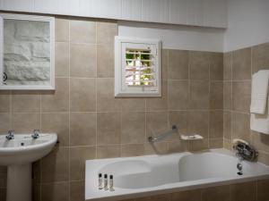 a bathroom with a bath tub and a sink at Fouriesburg Country Inn in Fouriesburg +57 photos