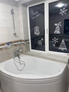 baño con bañera blanca y ventana en Дзембронія en Dzembronia