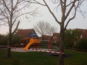 - une aire de jeux avec toboggan dans un parc arboré dans l'établissement Ferienwohnung Wilde, à Hooksiel