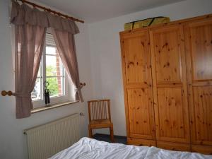 - une chambre avec un lit, une fenêtre et une armoire en bois dans l'établissement Ferienwohnung Wilde, à Hooksiel