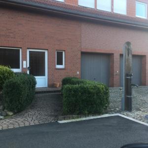 a brick building with two garage doors and bushes at Apartment-Vermietung wohnen-in-hope in Hameln
