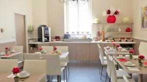 a restaurant with white tables and white chairs and a kitchen at Hôtel Helvétique in Nice