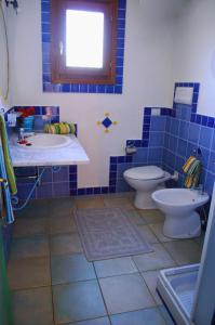 a blue tiled bathroom with a toilet and a sink at Vecchio Stazzo in San Teodoro