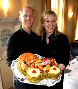 a man and a woman holding a large cake at Hotel Café Konditorei Köppel in Bingen am Rhein