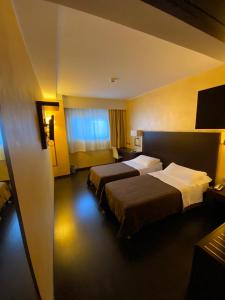 um quarto de hotel com duas camas e uma televisão em E' Hotel em Reggio di Calabria