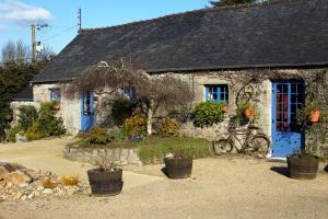 una casa de piedra con puertas azules y una bicicleta delante en Domaine Le Puits De Jeanne, en Plouégat-Moysan