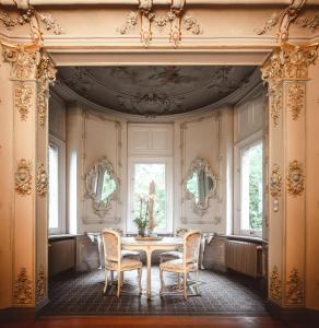 uma sala de jantar com mesa, cadeiras e janelas em Romantik Hotel Schloss Hohenstein em Ahorn