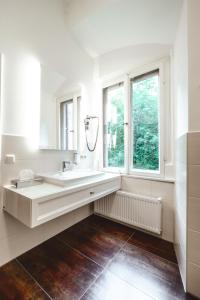 a white bathroom with a sink and a window at Romantik Hotel Schloss Hohenstein in Ahorn