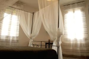 a bedroom with a bed with white curtains and a window at B&B Casa Bologna in Bologna