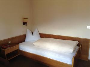 a small bed with white sheets and a night stand at Hotel Tannerhof in Merano