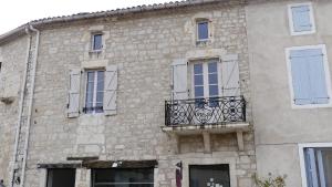 Montcuq的住宿－La Montcuquoise，带阳台和窗户的石头建筑