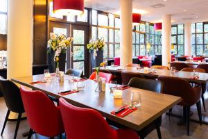 een eetkamer met tafels, stoelen en ramen bij Bastion Hotel Amsterdam Zuidwest in Amsterdam