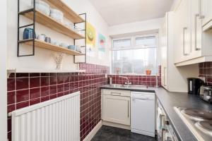 a kitchen with white cabinets and red tiles at GuestReady - Homely and Serene 1Bed Apartment in Islington in London