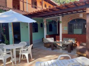 a patio with a table and chairs and an umbrella at Pousada Rota Tropicana in Arraial d'Ajuda
