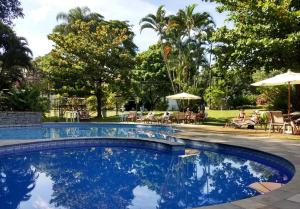a swimming pool in a resort with people sitting in chairs at Hotel Santa Amalia in Vassouras