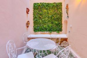 a patio with a table and chairs and a green hedge at Vintage Palma Palace Apartments TI by PriorityVillas in Palma de Mallorca +24 photos